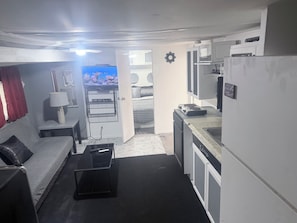 Un espace de vie compact comprenant un coin cuisine, un canapé, une table basse et un téléviseur.