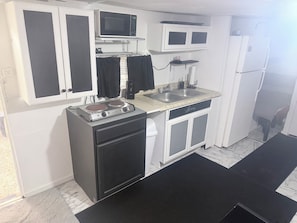 A compact kitchen with a microwave, stove, sink, and refrigerator.