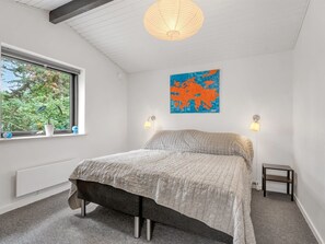 Ein Schlafzimmer mit Bett, Fenster, einer Wandleuchte und einer Karte als Kunstwerk.