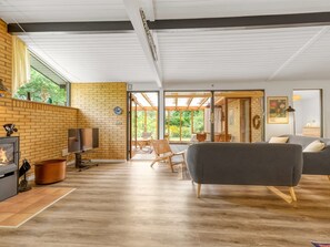 Ein modernes Wohnzimmer mit Kamin, einer Couch und einem Essbereich mit Blick ins Freie.