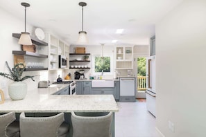 A modern kitchen with white cabinets, a marble countertop, and pendant lighting. - Close to Beach & Duck Town w Pool & New Updates! (Duck)