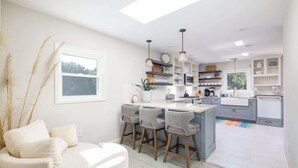 Una cocina moderna con taburetes de bar, un comedor con sofá y un ventanal grande.