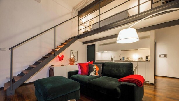 Una sala de estar moderna con escalera, un sofá y una lámpara colgante.