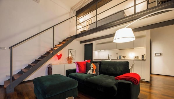 Ein modernes Wohnzimmer mit Treppe, einer Couch und einer Pendelleuchte.