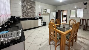 Una cocina moderna con comedor, que presenta una encimera negra, armarios blancos y un salpicadero con estampado.