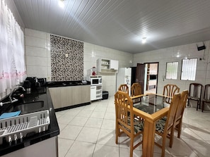 A modern kitchen with a dining area, featuring a black countertop, white cabinets, and a patterned backsplash. - casa grande praia da pinheira (Palhoça)