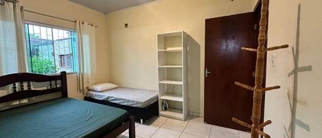 A bedroom with a bed, a wardrobe, a shelf unit, and a door.