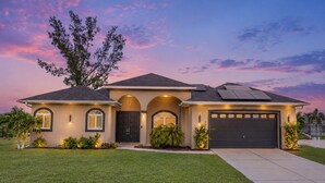 Une maison à deux étages avec un garage, des panneaux solaires et une pelouse bien entretenue.