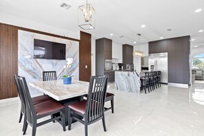Una cocina moderna con salpicadero de mármol, televisor integrado y comedor con mesa y sillas de mármol.