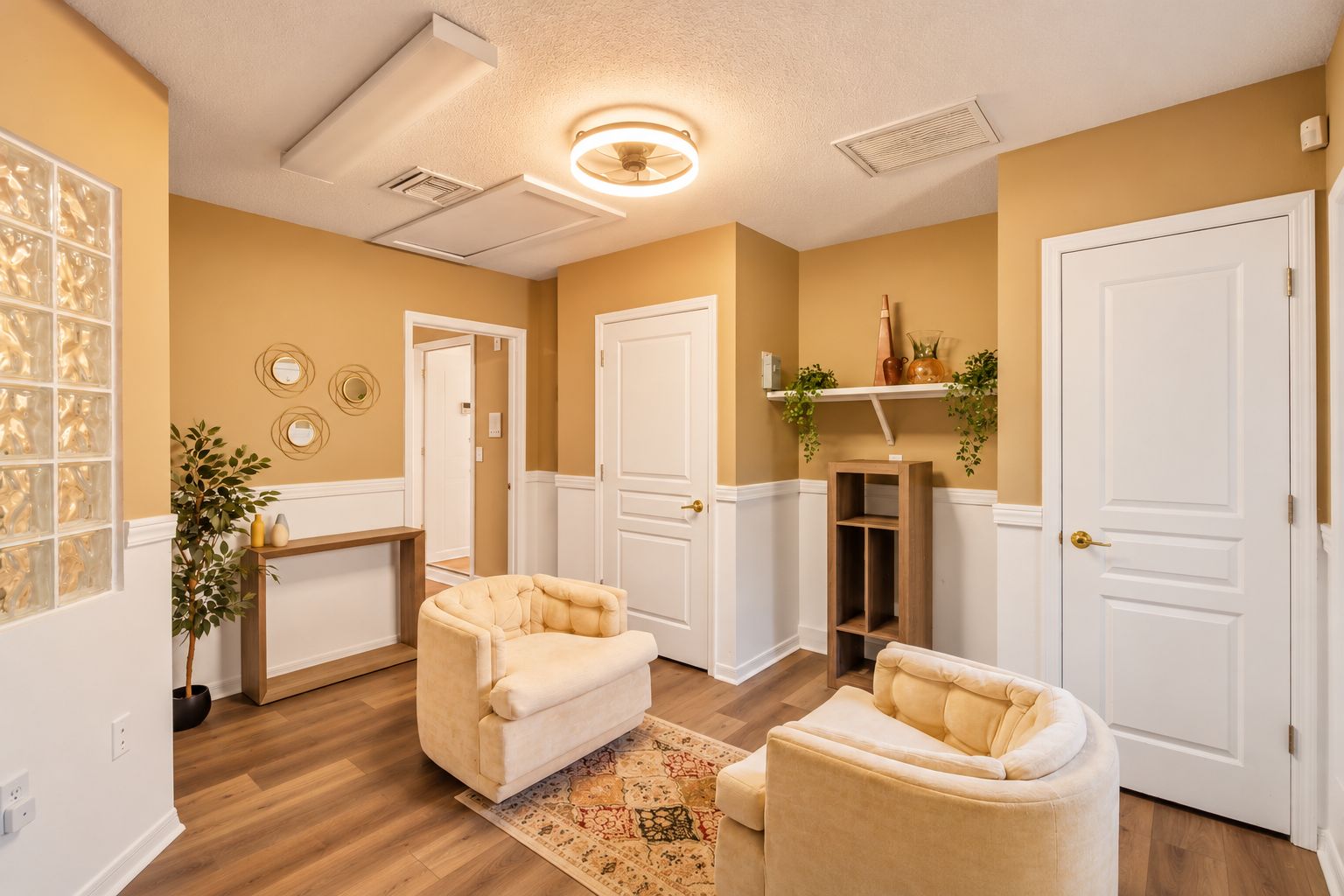 A hallway with two cream-colored armchairs, a wooden console table, and a decorative mirror.