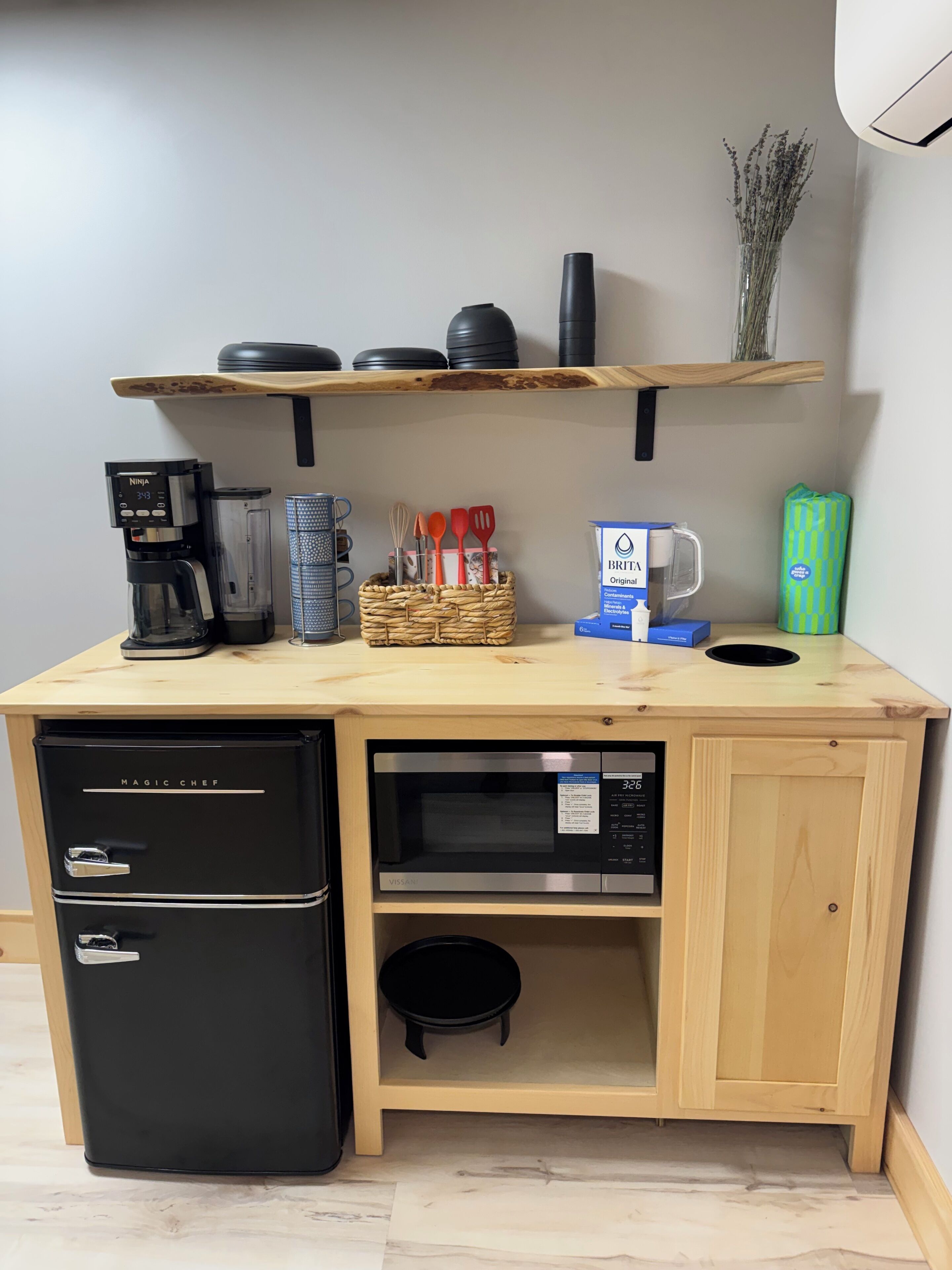 Una cucina compatta con macchina da caffè, forno a microonde e cassetti contenitori.