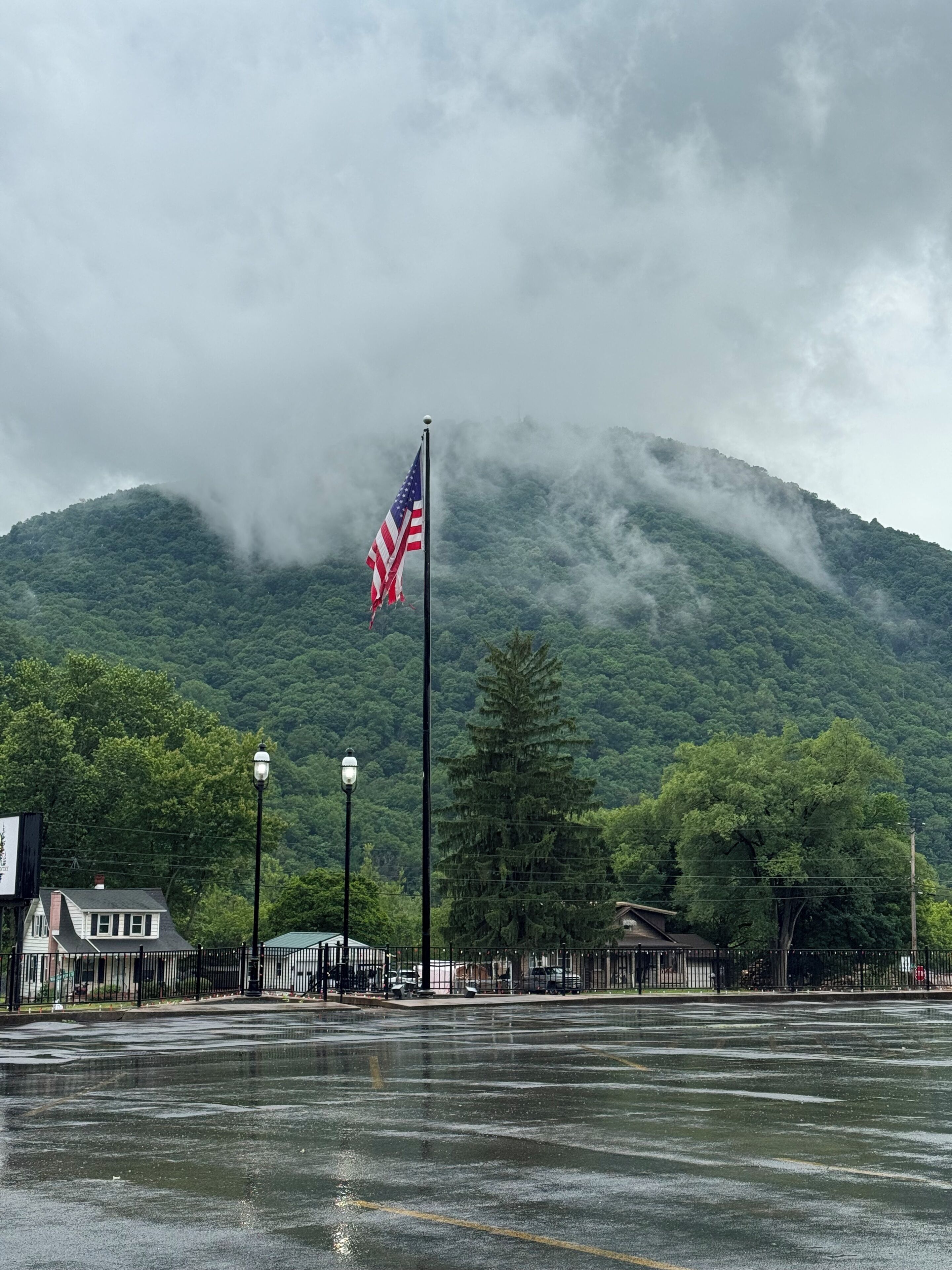 A flagpole with an American flag, a street lamp, and a mountain in the background.