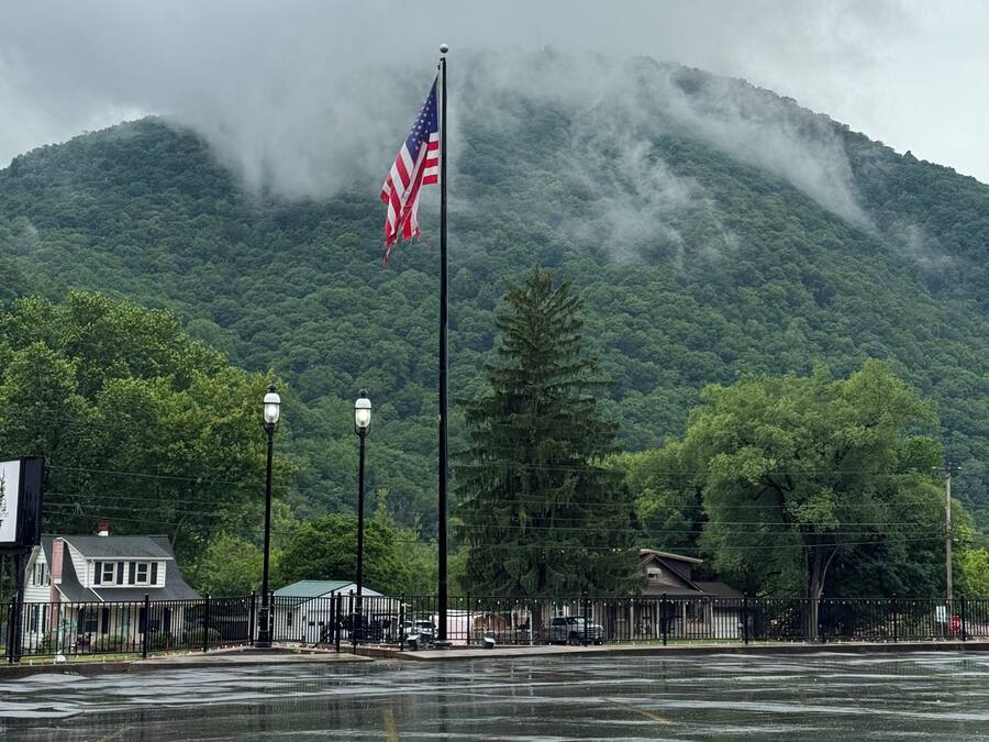 A flagpole with an American flag, a street lamp, and a mountain in the background.
