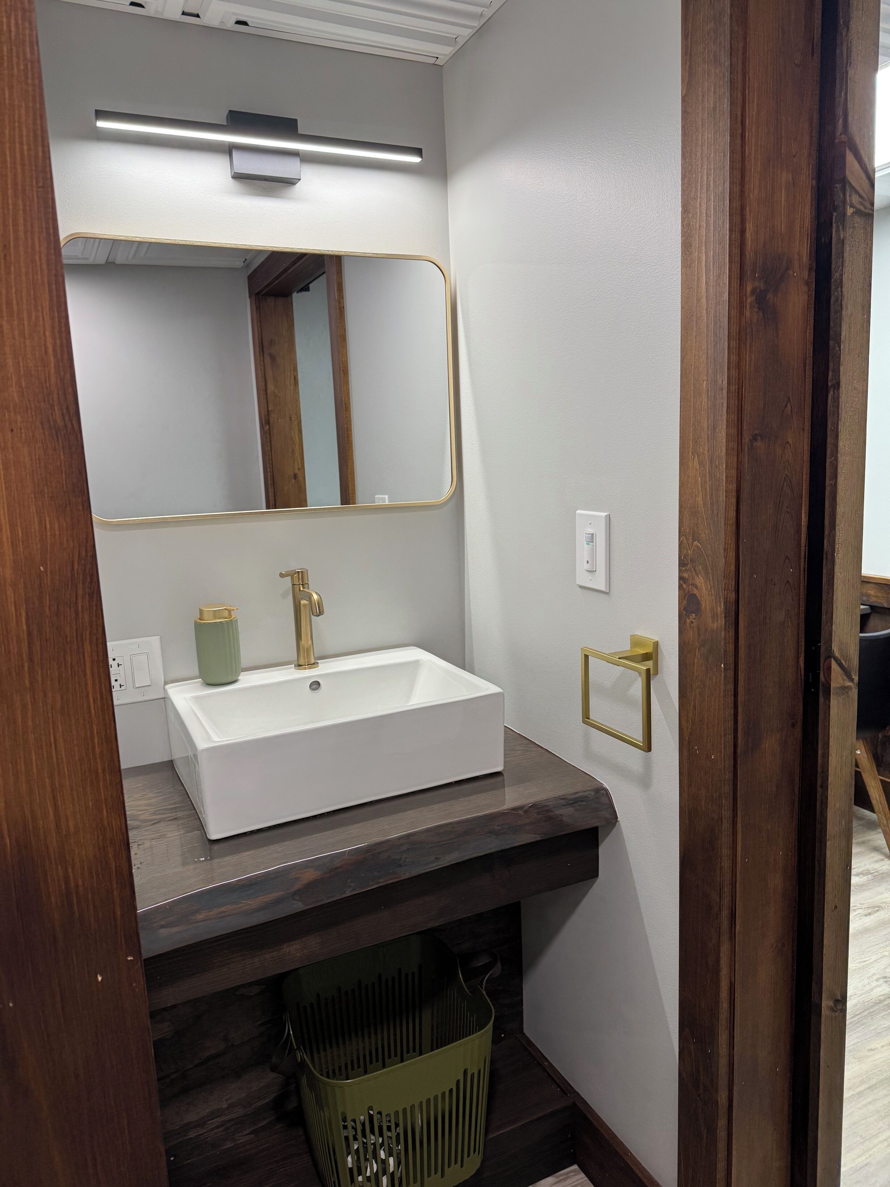 A bathroom with a white sink, gold faucet, and a mirror with a gold frame.