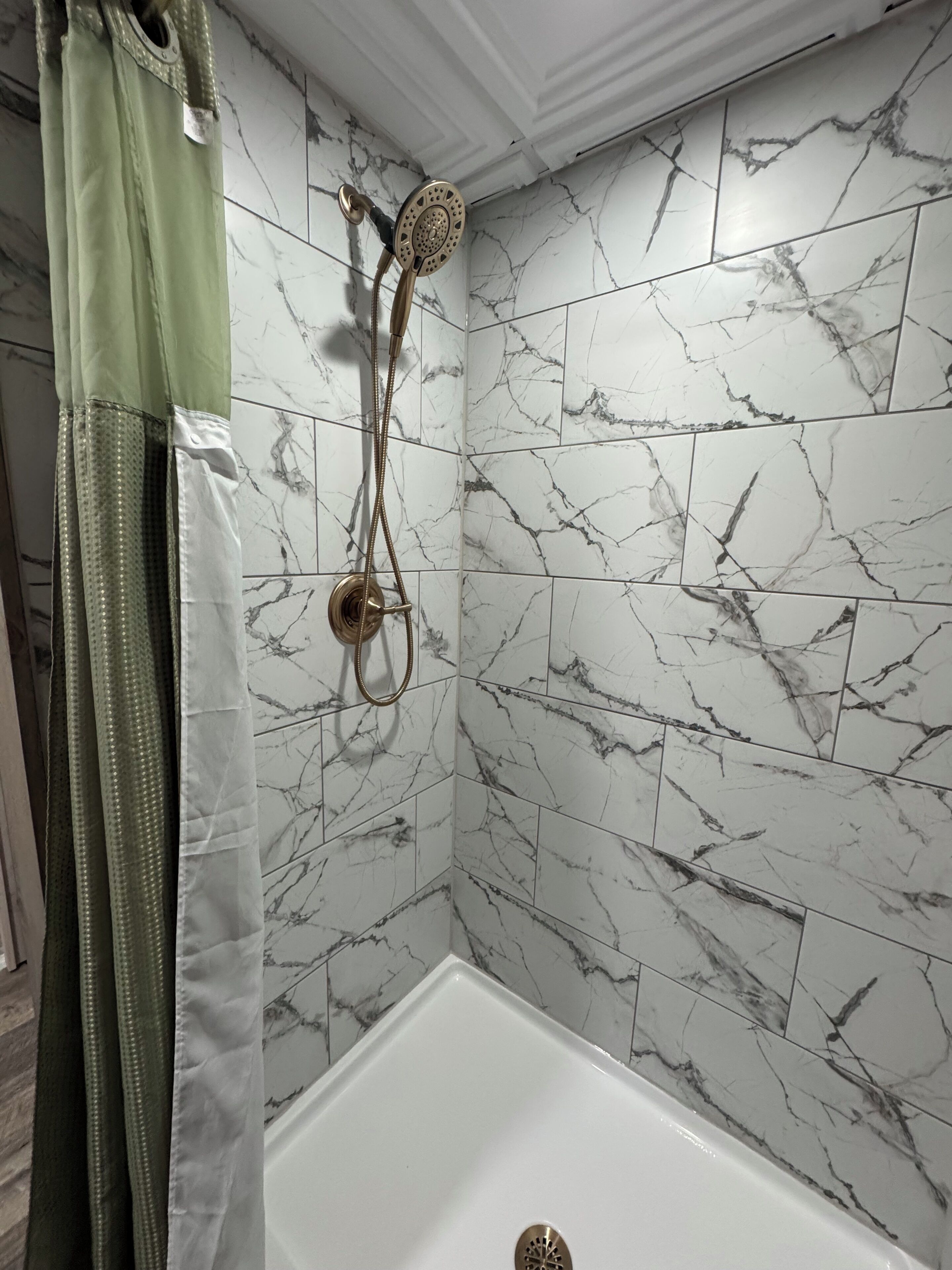 A bathroom with a shower, a bathtub, and marble-patterned walls.