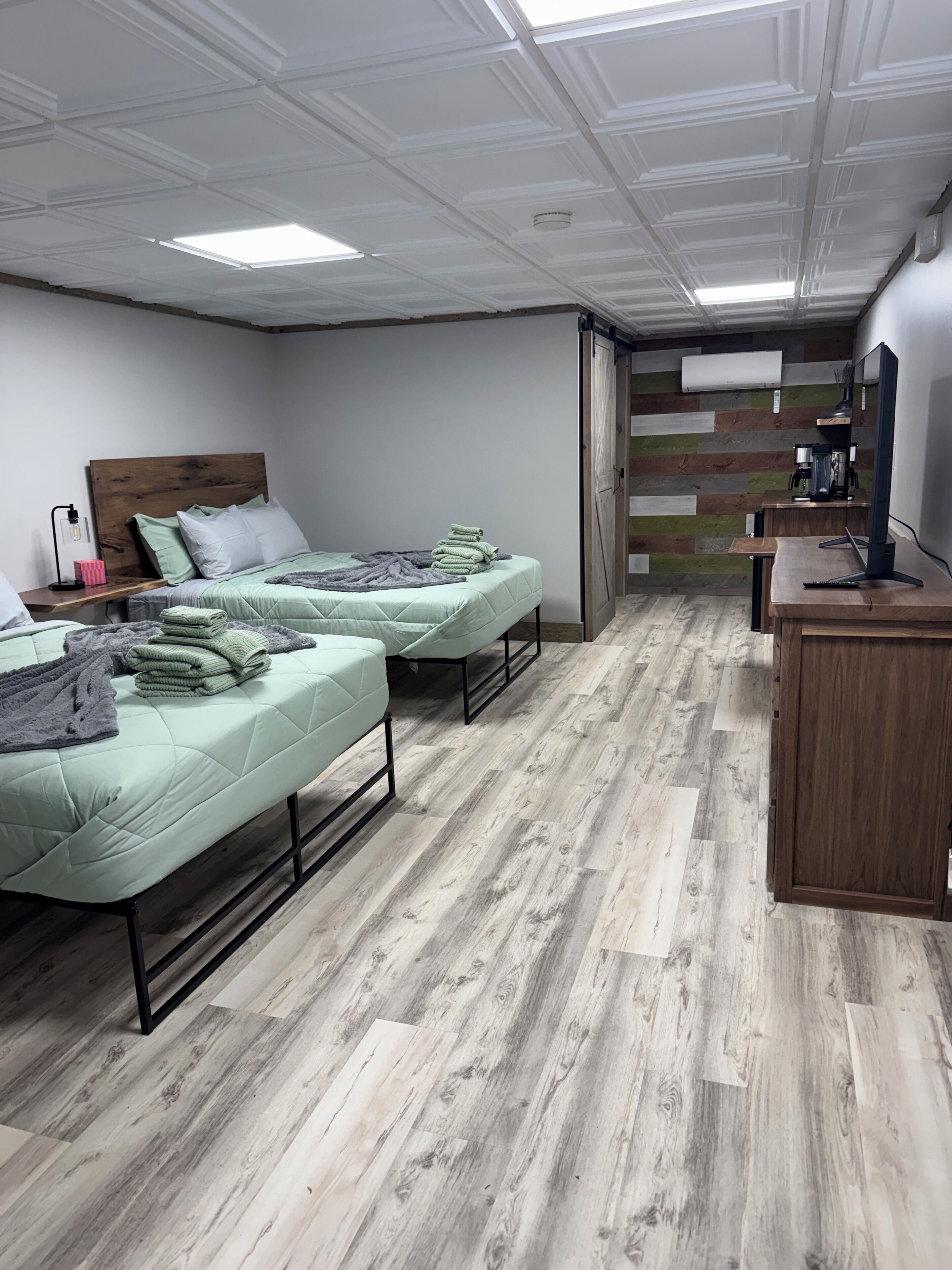 Un dormitorio con dos camas, un escritorio, una computadora y un aire acondicionado de pared.