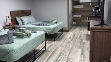 Un dormitorio con dos camas, un escritorio, una computadora y un aire acondicionado de pared.