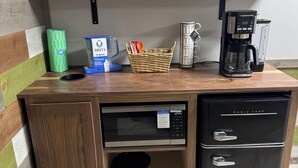 A compact kitchenette with a microwave, coffee maker, and a small refrigerator.