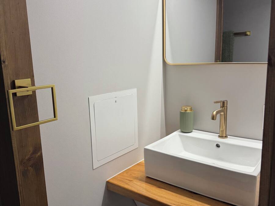 Een badkamer met een wit wastafel, een spiegel met gouden lijst en een houten aanrecht.