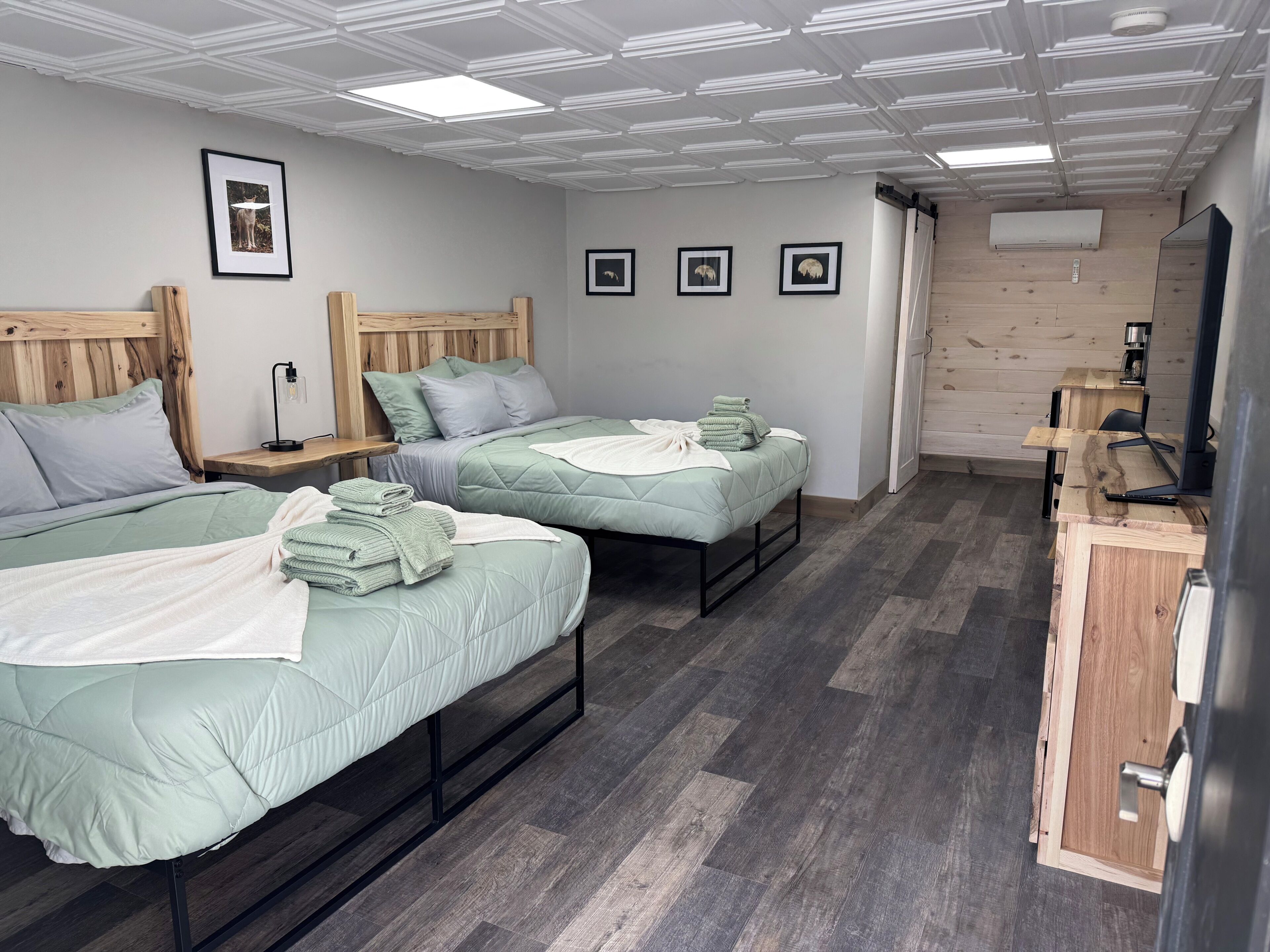 A room with two beds, a wooden headboard, a desk, and a mirror.