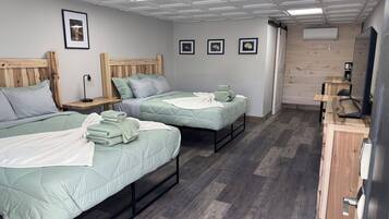 A room with two beds, a wooden headboard, a desk, and a mirror.
