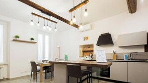 A modern kitchen with wooden beams, pendant lights, a central island, and built-in appliances. - Aquarium 3' | 2BR | A/C | Wifi & Netflix by Tilo (Genoa)