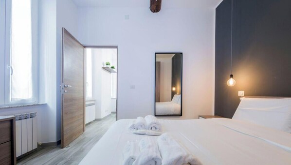 Ein Hotelzimmer mit einem Bett, einem Nachttisch, einem Spiegel, einem Fenster und einer Tür zu einem Badezimmer.