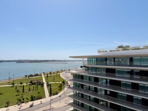 A modern building with multiple floors, a rooftop garden, and a view of a body of water. - Barreiro Nooba 263C Apartment BY LULUNA (Barreiro)