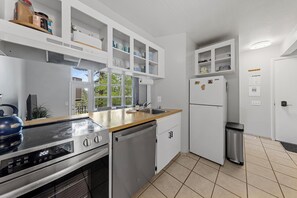 Eine moderne Küche mit weißen Schränken, einem Edelstahl-Geschirrspüler, einem Einbauofen und einem Kühlschrank.