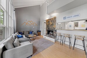 Ein modernes Wohnzimmer mit grauem Sofa, einem Steinkamin und einer Bar.