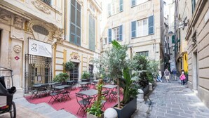Ein Straßencafé mit Tischen und Stühlen, umgeben von Gebäuden im klassischen Stil.