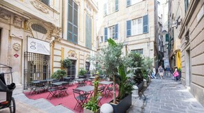 Ein Straßencafé mit Tischen und Stühlen, umgeben von Gebäuden im klassischen Stil.