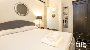 Ein Hotelzimmer mit einem Bett, einem runden Spiegel, einer Wand-Klimaanlage, einer Lampe und einem dunklen Holzschrank.