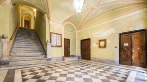 Eine prachtvolle Eingangshalle mit Schachbrettfußboden, einer Treppe und Holztüren.