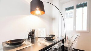 Eine moderne Küche mit schwarzem Arbeitsplatz, einer Kaffeemaschine, einem Wasserkocher und einem Glas.