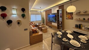 Una sala de estar moderna con un sofá, una mesa de comedor dispuesta para cuatro personas y un televisor montado en la pared.