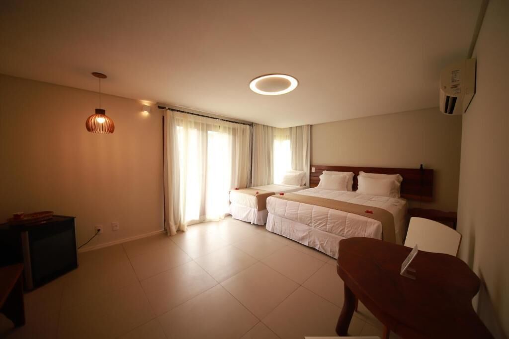 A hotel room with a bed, bedside tables, a desk, and a chair.