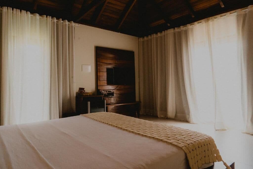 A bedroom with a bed, a wooden dresser, and a mirror on the wall.