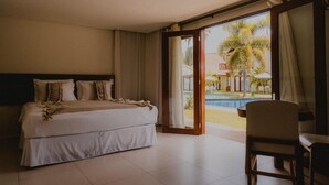A hotel room with a bed, a chair, and a view of a swimming pool. - Pousada Rangai (Maragogi)