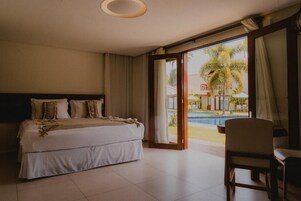 Quarto de hotel com cama, uma cadeira e vista para uma piscina.