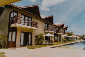 Hotel com várias varandas, piscina e área de estar ao ar livre.