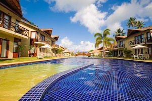 Um hotel com piscina, varandas e palmeiras.