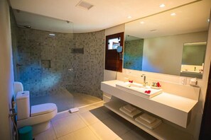 A modern bathroom with a glass-enclosed shower, a white sink with a large mirror, and a toilet. - Pousada Rangai (Maragogi)