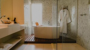 A modern bathroom with a glass-enclosed shower, a white bathtub, and a vanity with a mirror and sink. - Pousada Rangai (Maragogi)