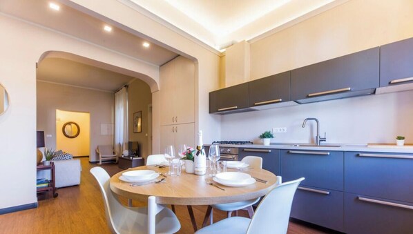 A modern kitchen with dark cabinets, a round dining table, and a small island. - Aquarium 3'|2BR|Lift|Wifi|Train Station|By Tilo (Genova)