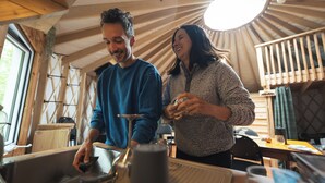 Un interior rústico con vigas de madera, una zona de cocina y un comedor.