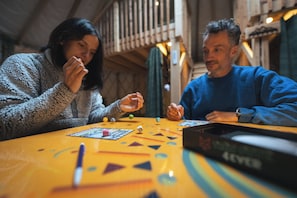 Two people playing a board game at a table with dice and game pieces. - Cozy Yurt in the Woods (Sainte-Agathe-des-Monts)