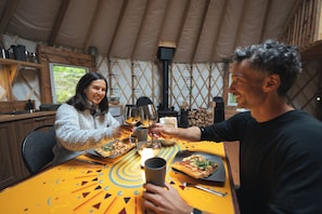 Una mesa de comedor con pizza, copas de vino y una vela.