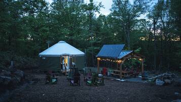 A tent and a small pavilion with seating, surrounded by trees.