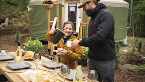 Una carpa con una mesa dispuesta para una comida, que incluye queso, vino y pan.